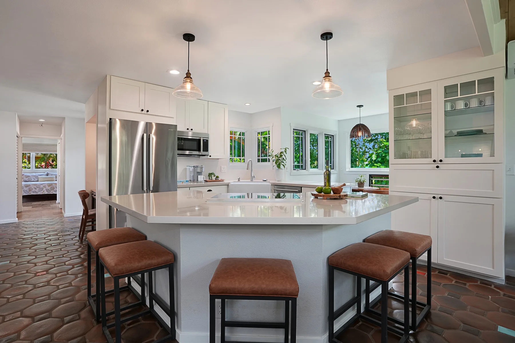 Una cocina luminosa con una isla grande, asientos de barra y ventanas.