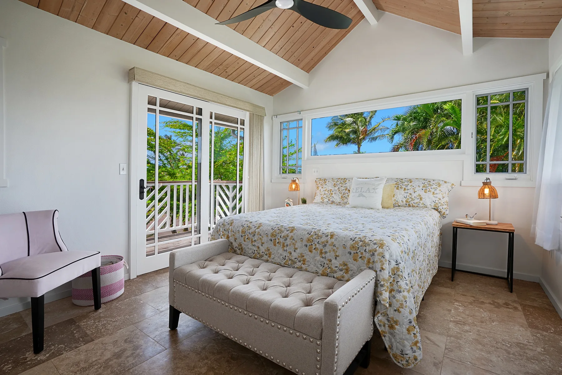 A bright bedroom with a floral bed and a high wood-plank ceiling.