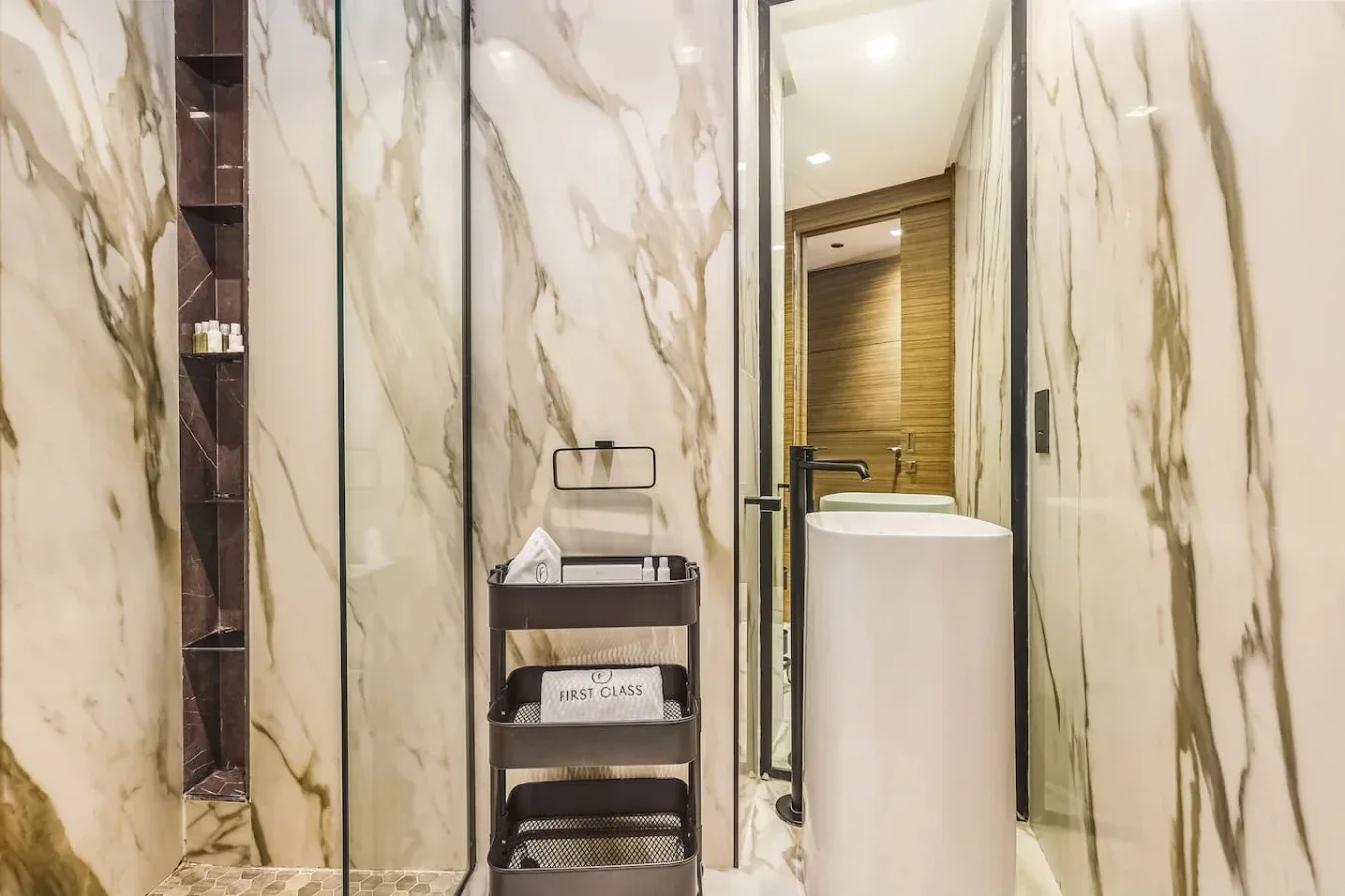 Un baño con lavabo exento y paredes con vetas de mármol.