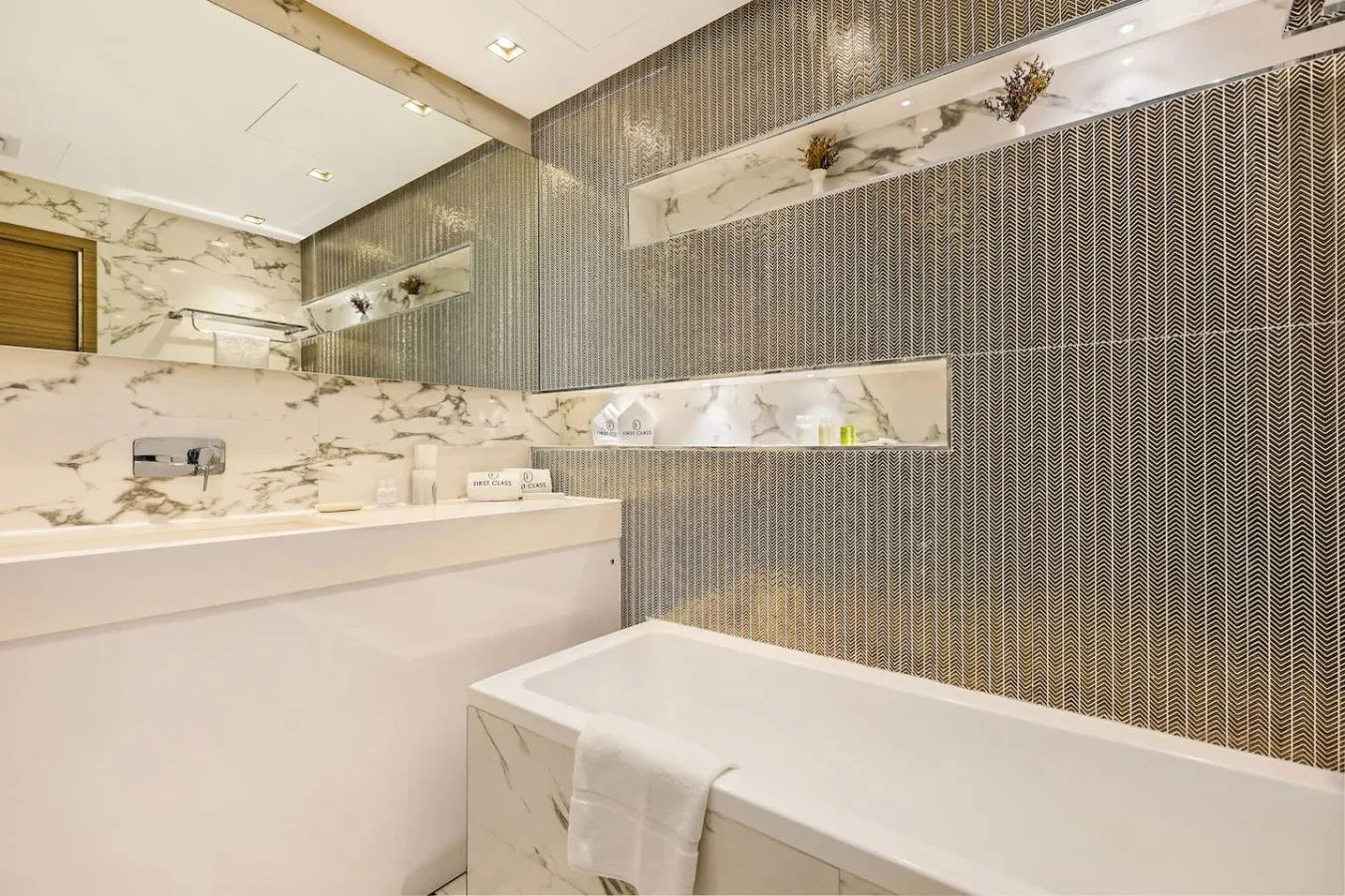 Un baño con bañera, lavabo y azulejos estampados en la pared.