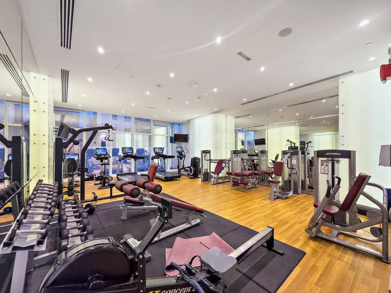 Un gimnasio con equipos de ejercicio distribuidos en una sala luminosa.