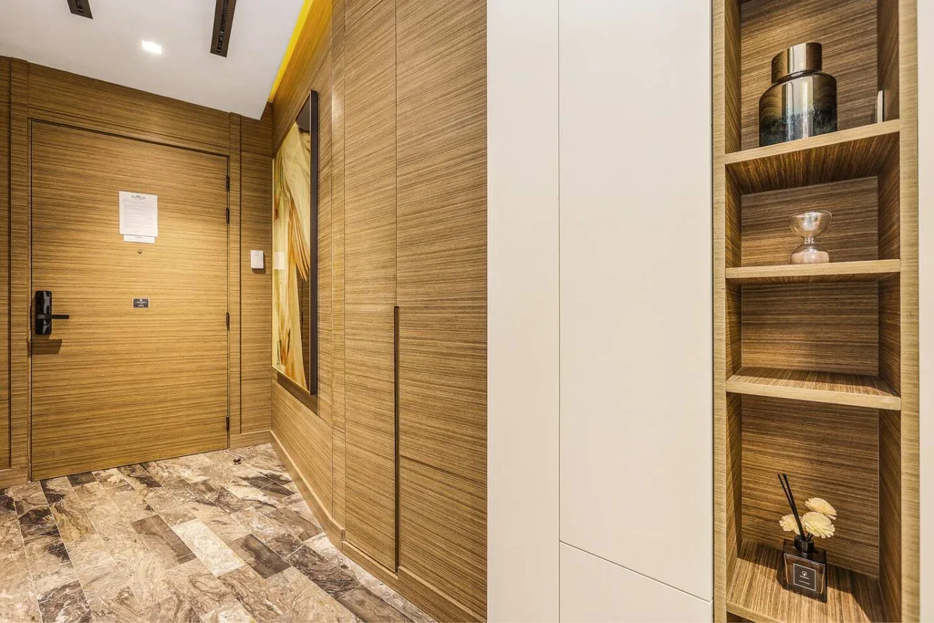 Un pasillo de entrada revestido de madera, con suelo estampado y estanterías empotradas.