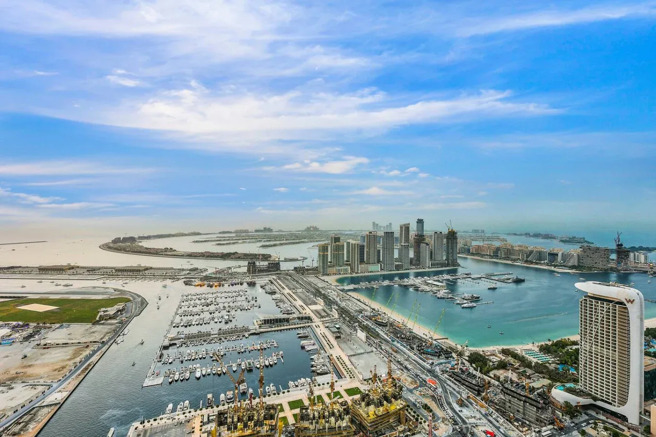 Vista aérea de una marina y edificios junto al agua bajo un amplio cielo azul.