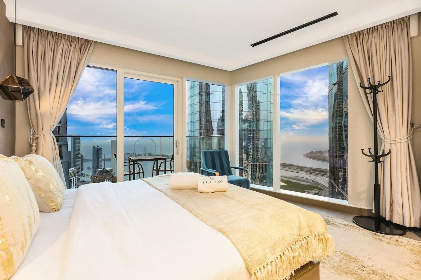 Un dormitorio con una cama junto a ventanales con vistas a la ciudad y la costa.