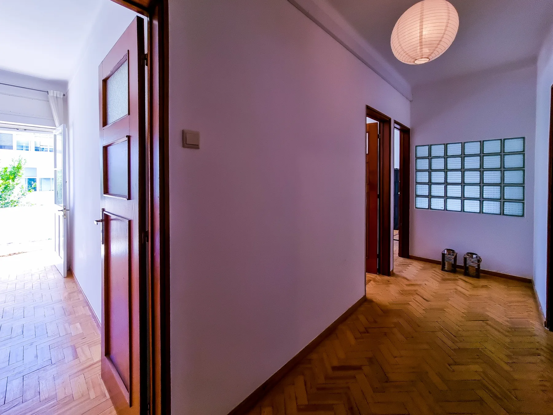 A bright interior hallway with wooden doors and parquet flooring.