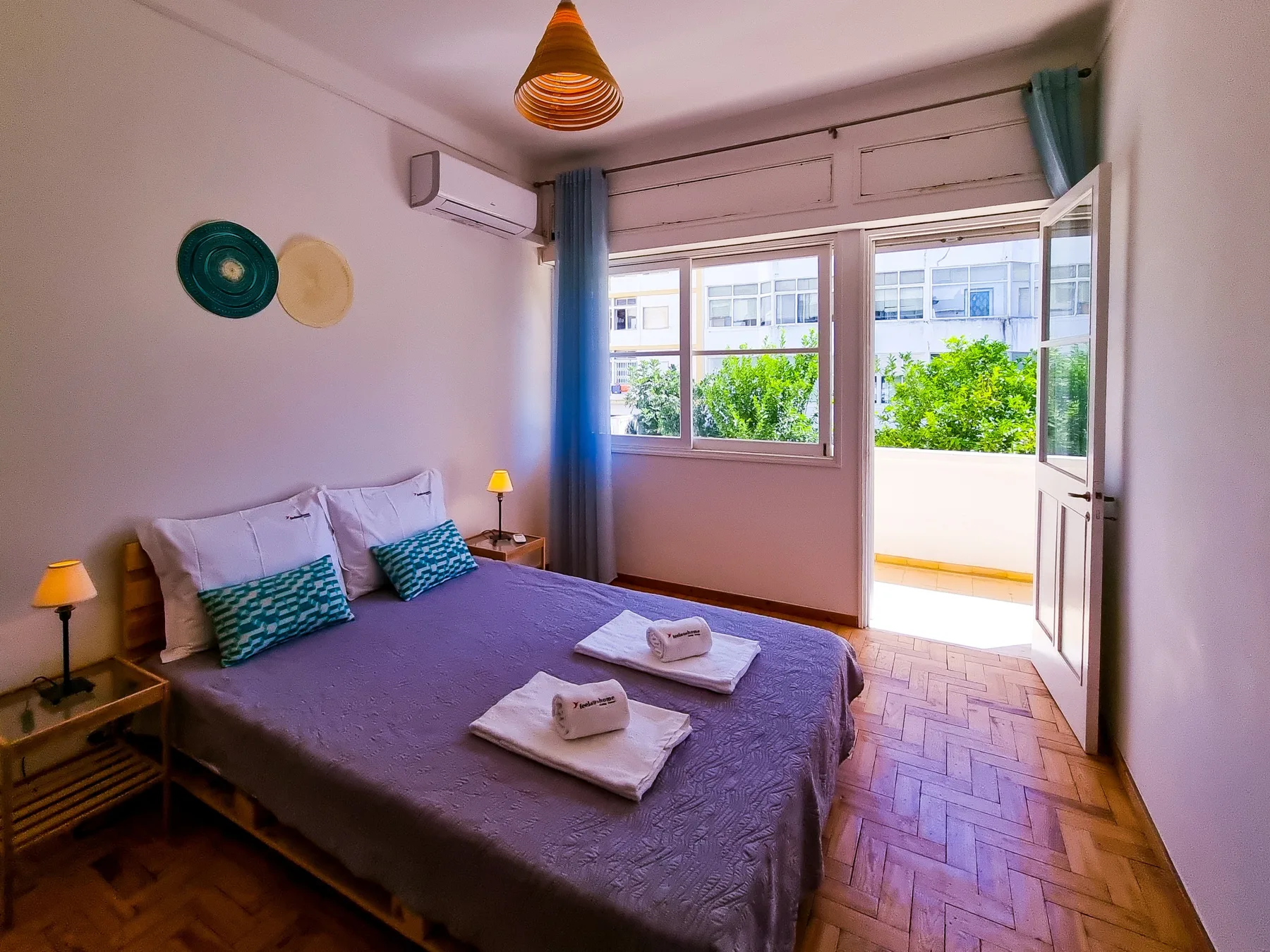 A bedroom with a double bed and an open door to the balcony.