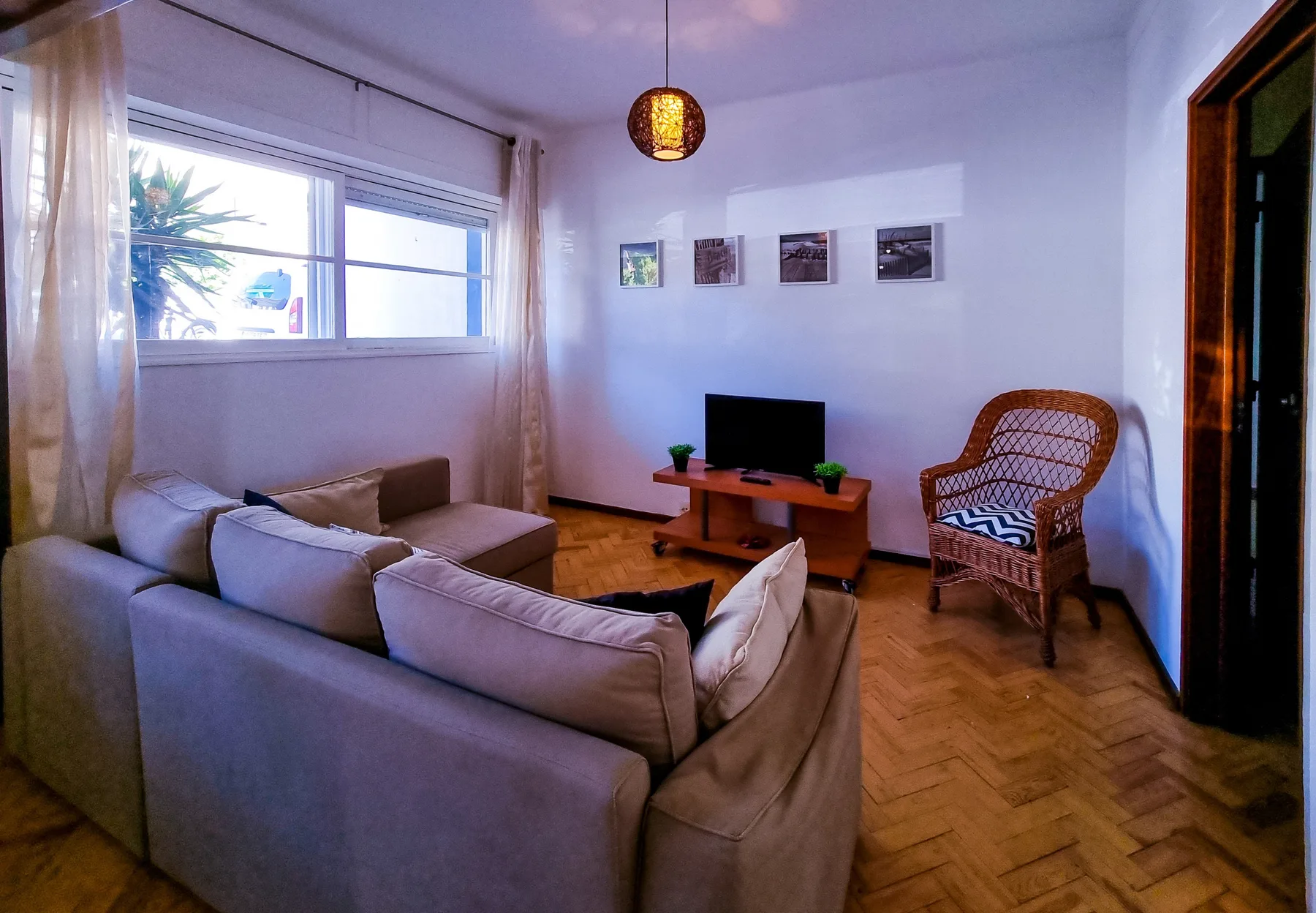 A living room with seating, a television, and a woven chair.
