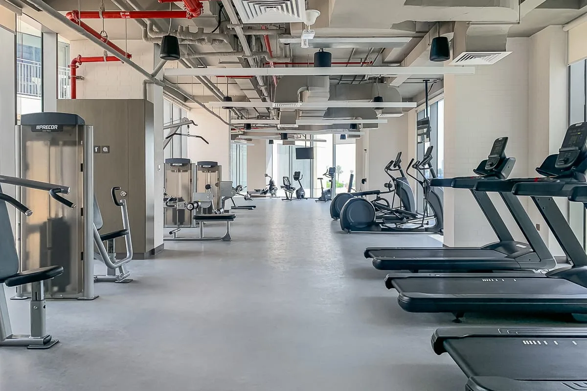 Un gimnasio amplio con máquinas de ejercicio y cintas de correr.