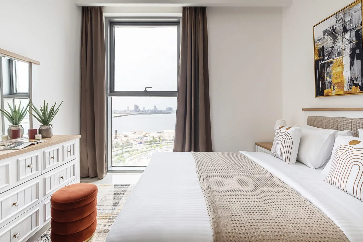 Un dormitorio luminoso con una gran ventana que da al agua y la ciudad.