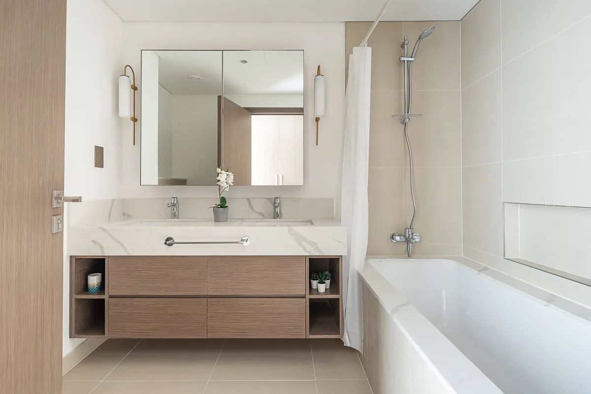 Un baño luminoso con un lavabo doble y una bañera.
