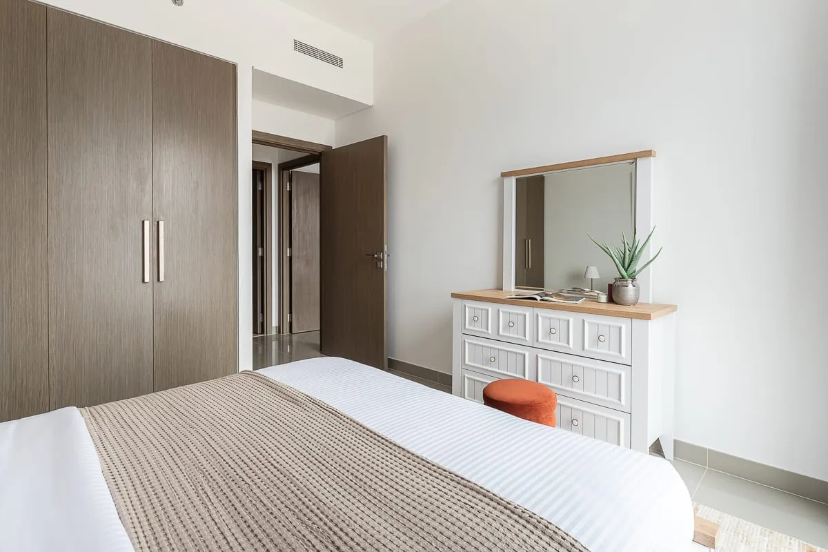 Un dormitorio con una cama ordenada, un armario y una cómoda.