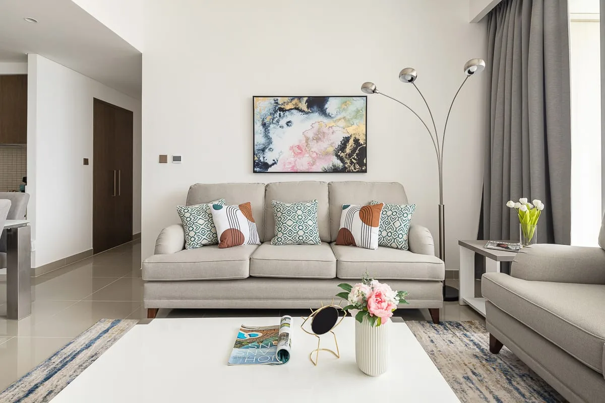 A bright living room with a sofa, colorful cushions, and artwork on the wall.
