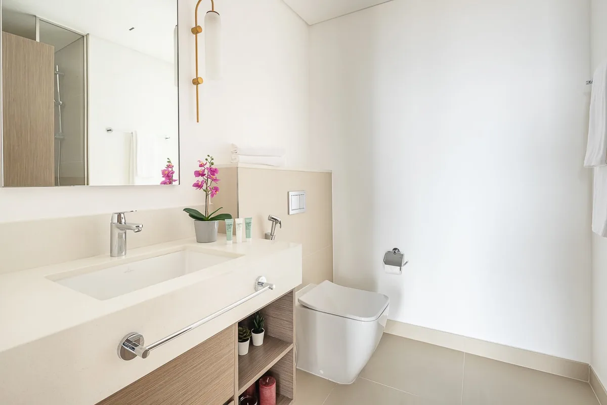 Un baño luminoso con un tocador largo, lavabo e inodoro.