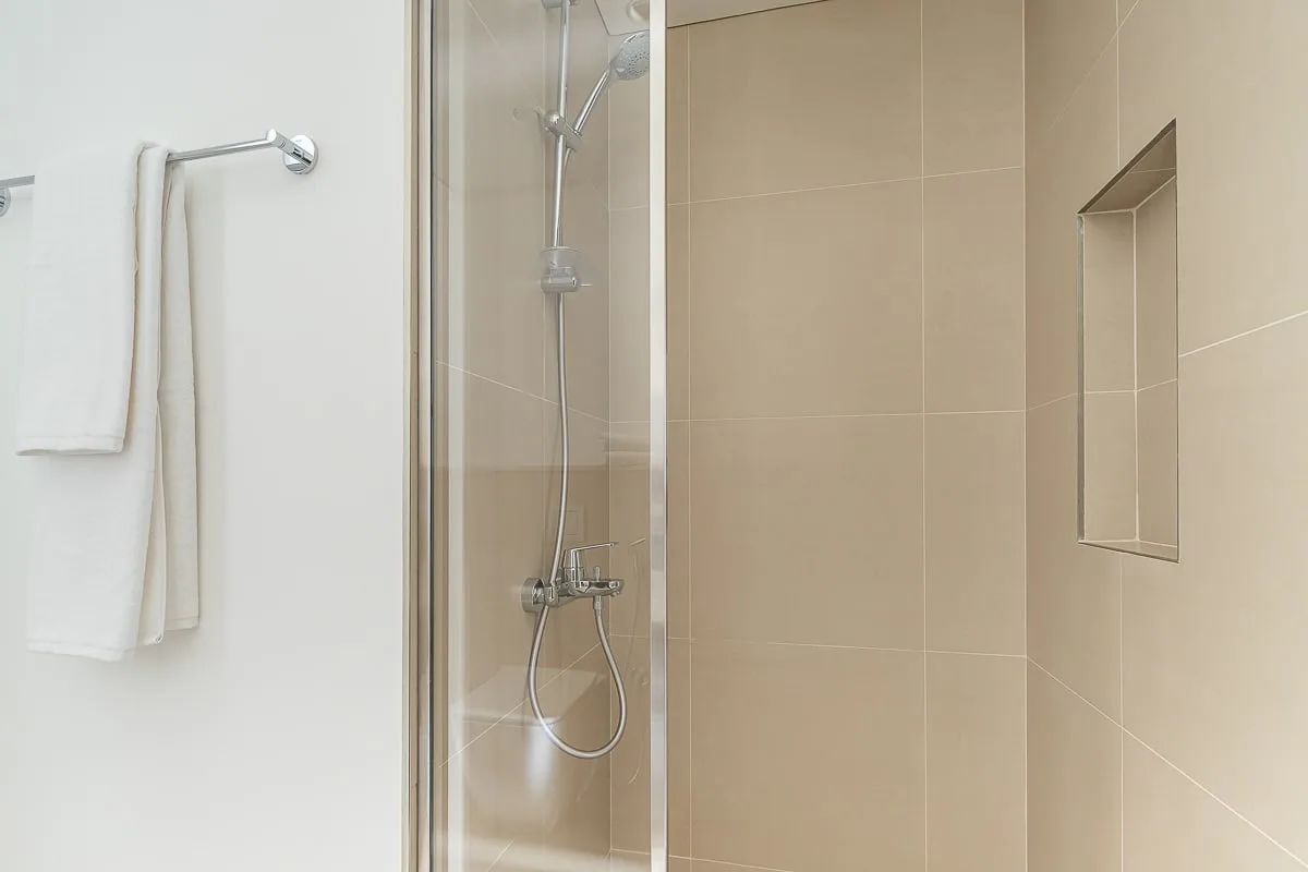 Zona de ducha en un baño alicatado, con grifería de pared y un nicho empotrado.