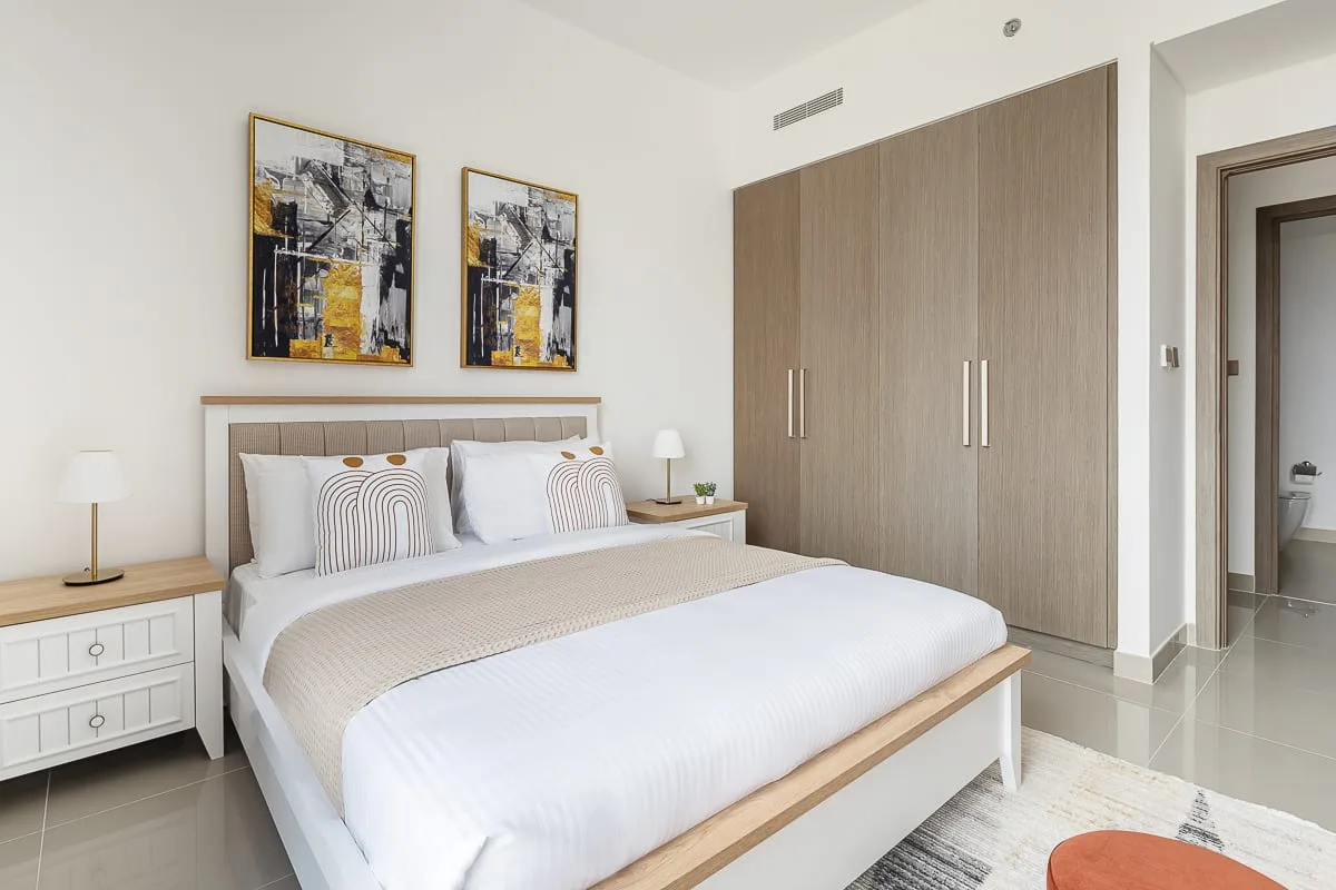 Un dormitorio luminoso con una cama bien hecha y un armario grande.