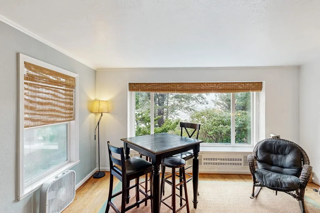 A bright dining area with a table beside a large window overlooking greenery.
