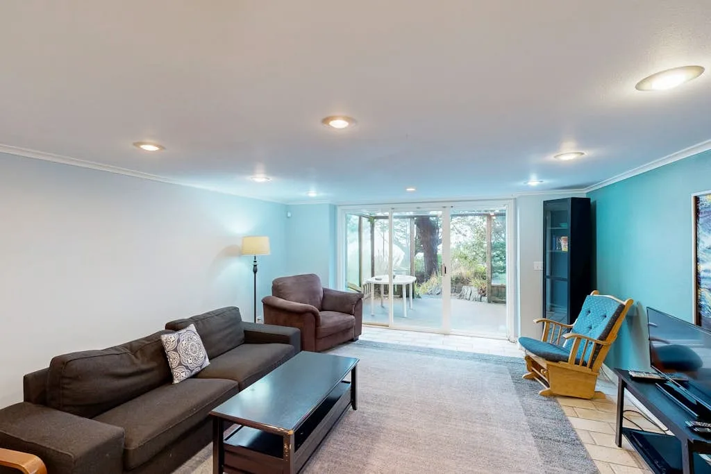 A bright living room with seating and sliding glass doors opening to a garden.