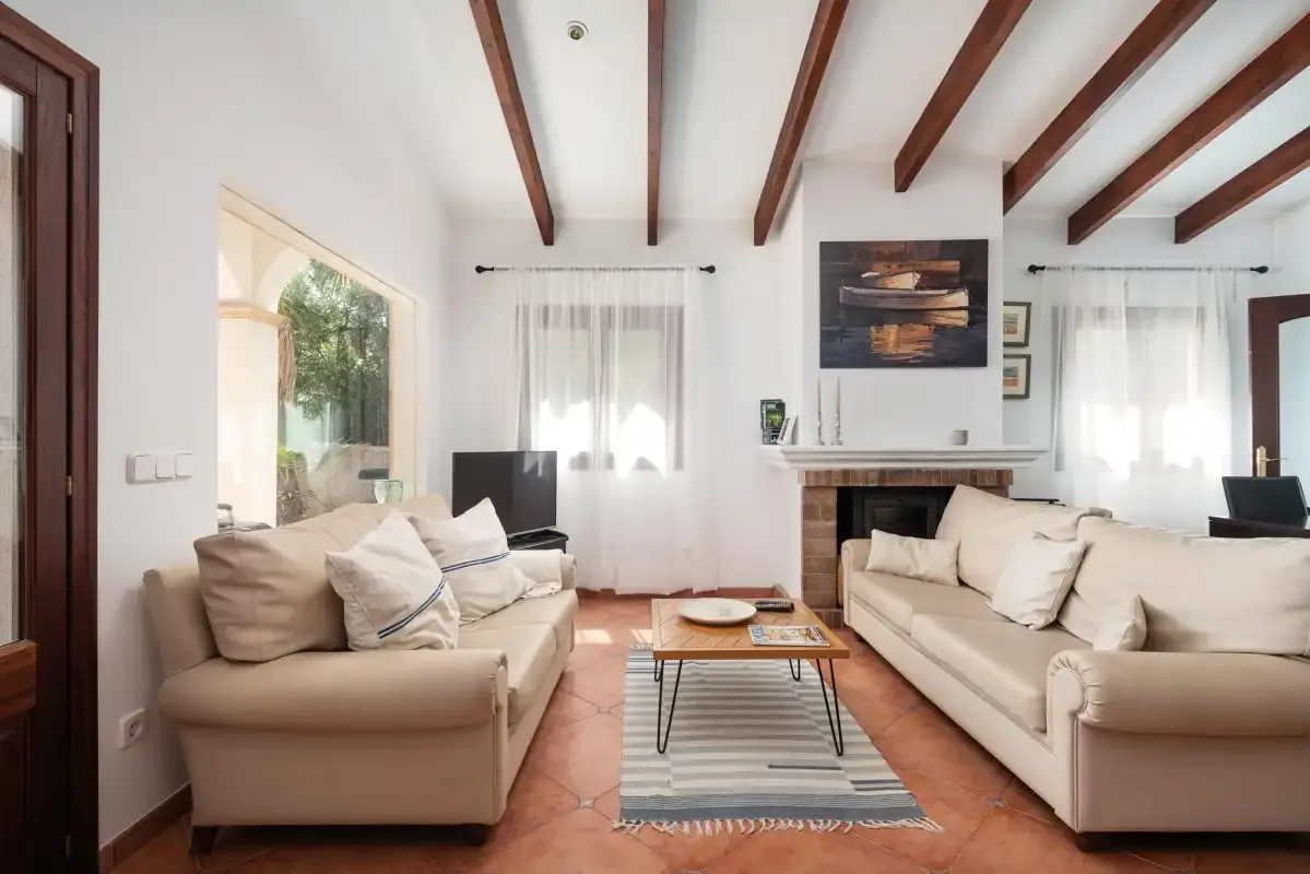 A bright living room with seating arranged around a coffee table and fireplace.