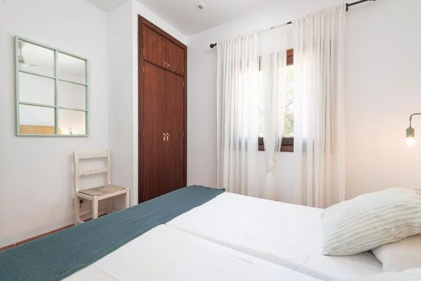 A bedroom with a bed, a wooden wardrobe, and a curtained window.