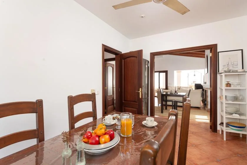 A dining area with a wooden table set with fruit and drinks.