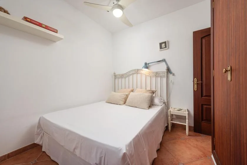 A bedroom with a neatly made bed and a small bedside table.