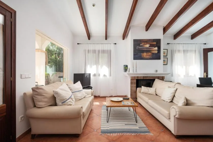 A bright living room with sofas, a coffee table, and exposed ceiling beams.