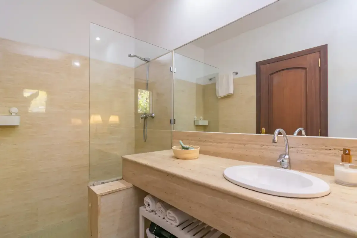 A bathroom with a glass shower, a long countertop, and a sink.