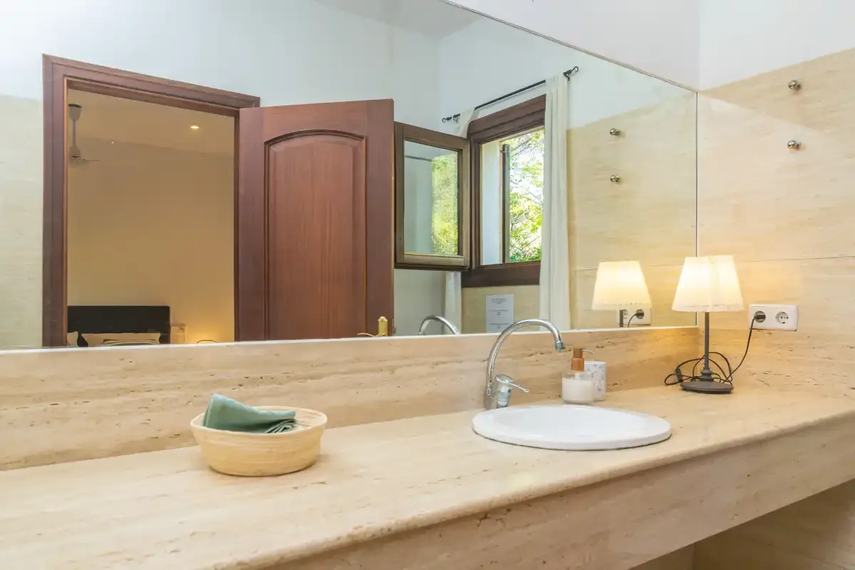 A bathroom vanity with a wide mirror and a sink beneath a window.