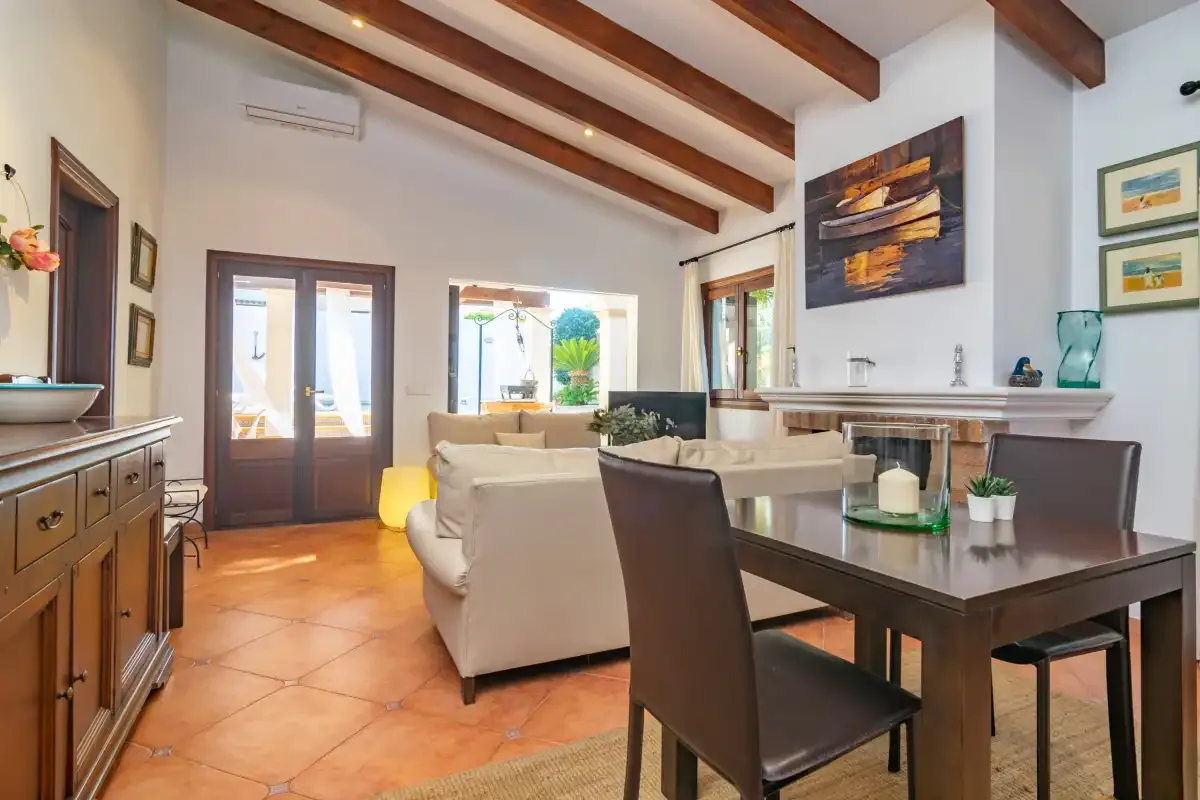A bright living and dining area has exposed ceiling beams and large windows.