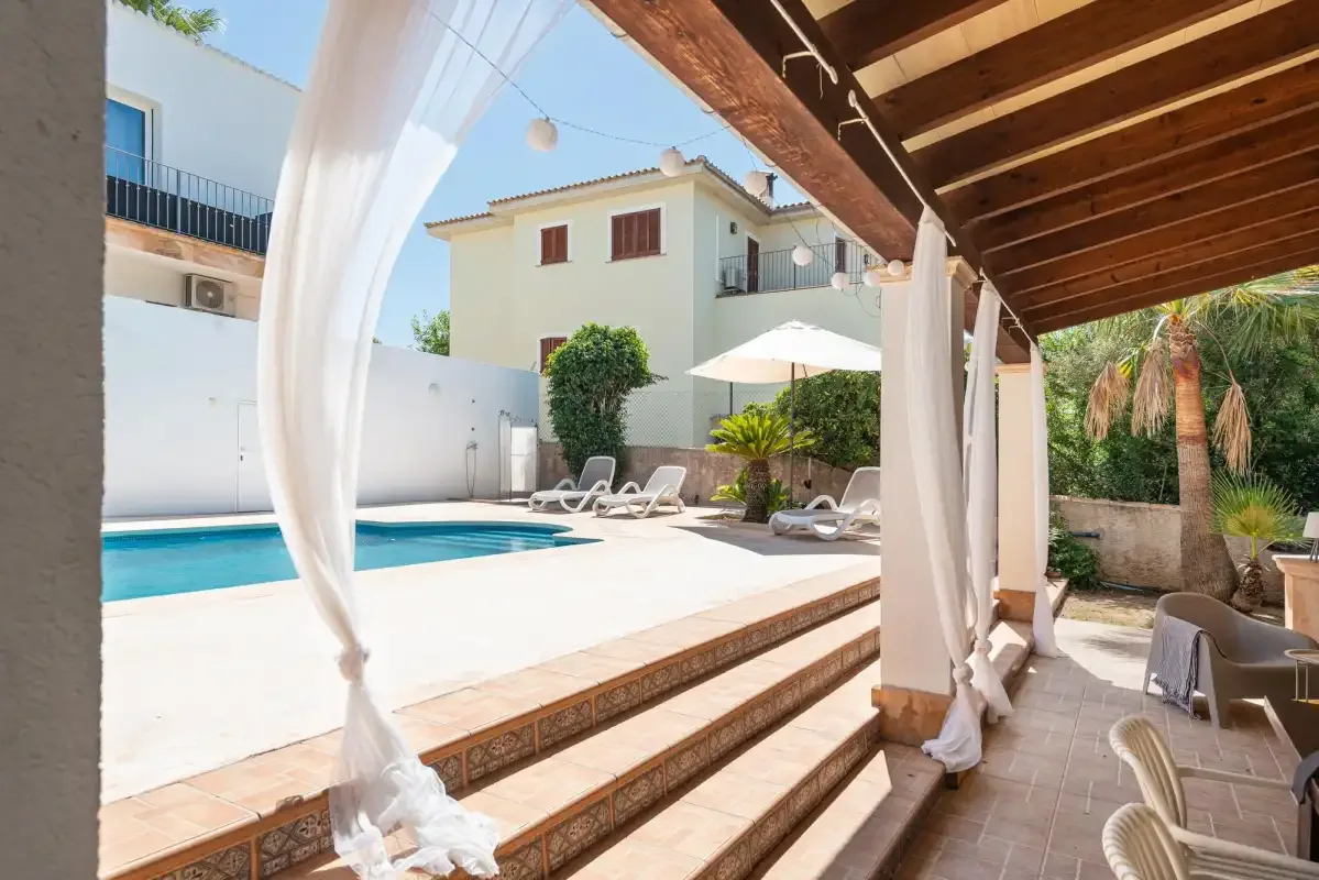 A swimming pool and lounge seating beside a shaded patio.