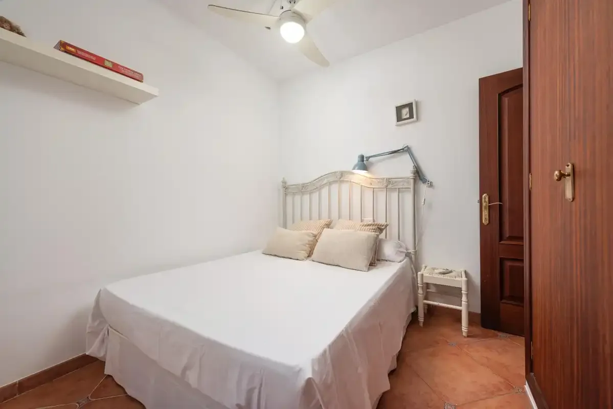 A bedroom with a bed, bedside table, and wooden door.