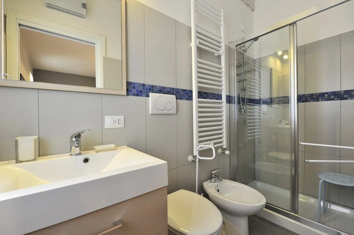 Un baño con un lavabo amplio, inodoro y ducha con mampara de vidrio.