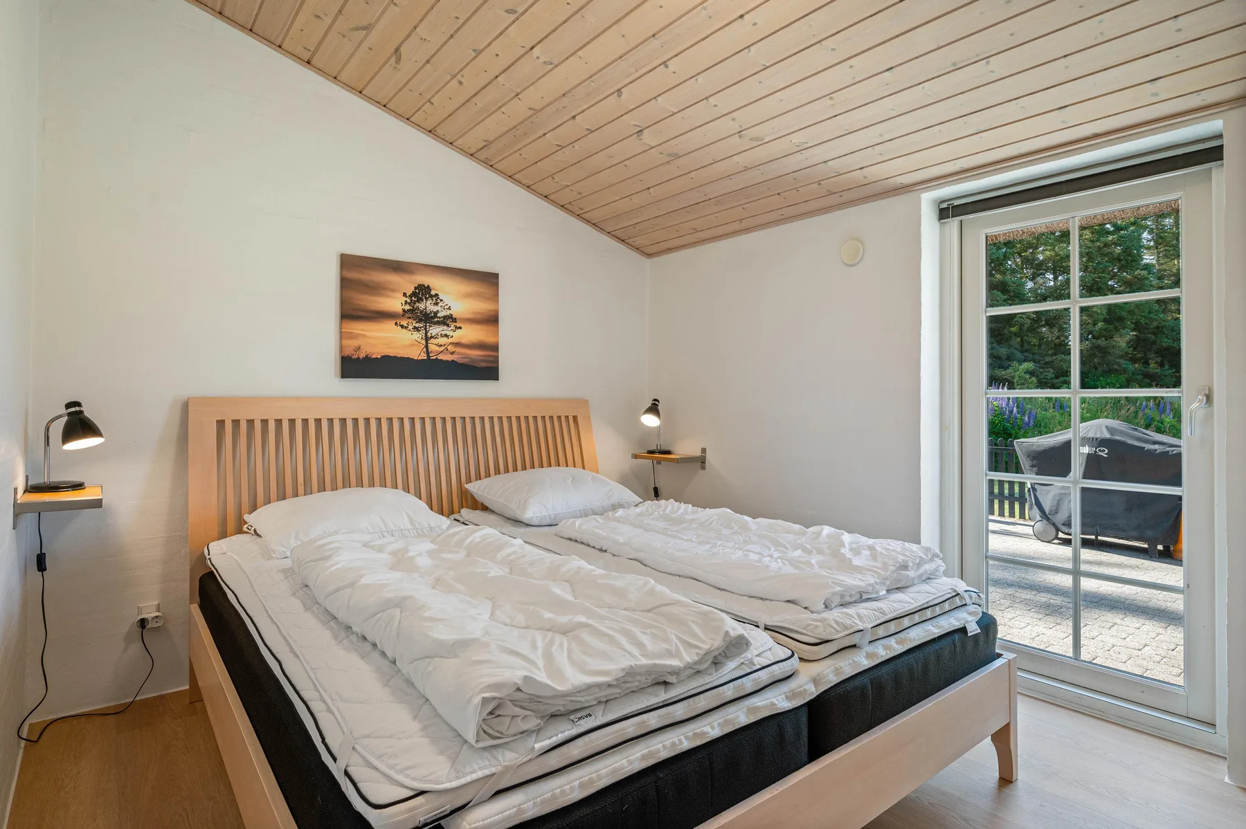Un dormitorio con una cama doble y una puerta de vidrio que da a un patio exterior.