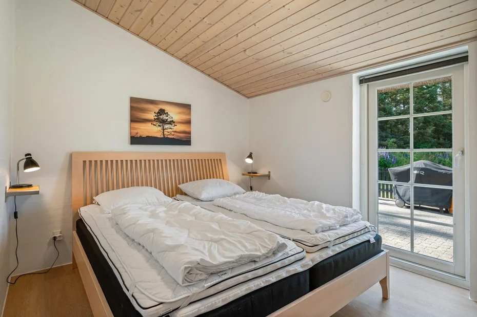 Un dormitorio con una cama doble y una puerta de vidrio que da a un patio.