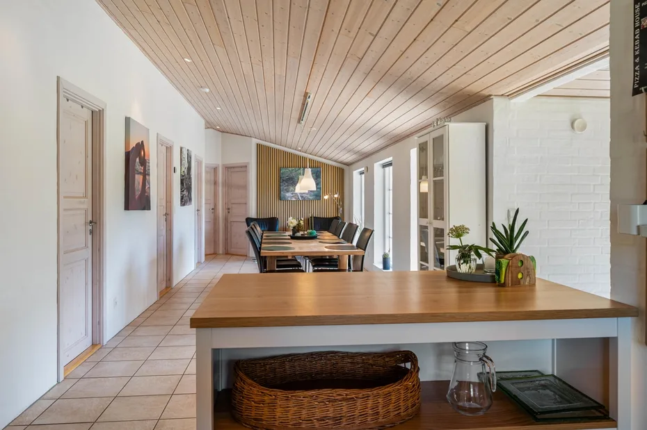 Un comedor luminoso con una mesa larga de madera y suelo de baldosas.