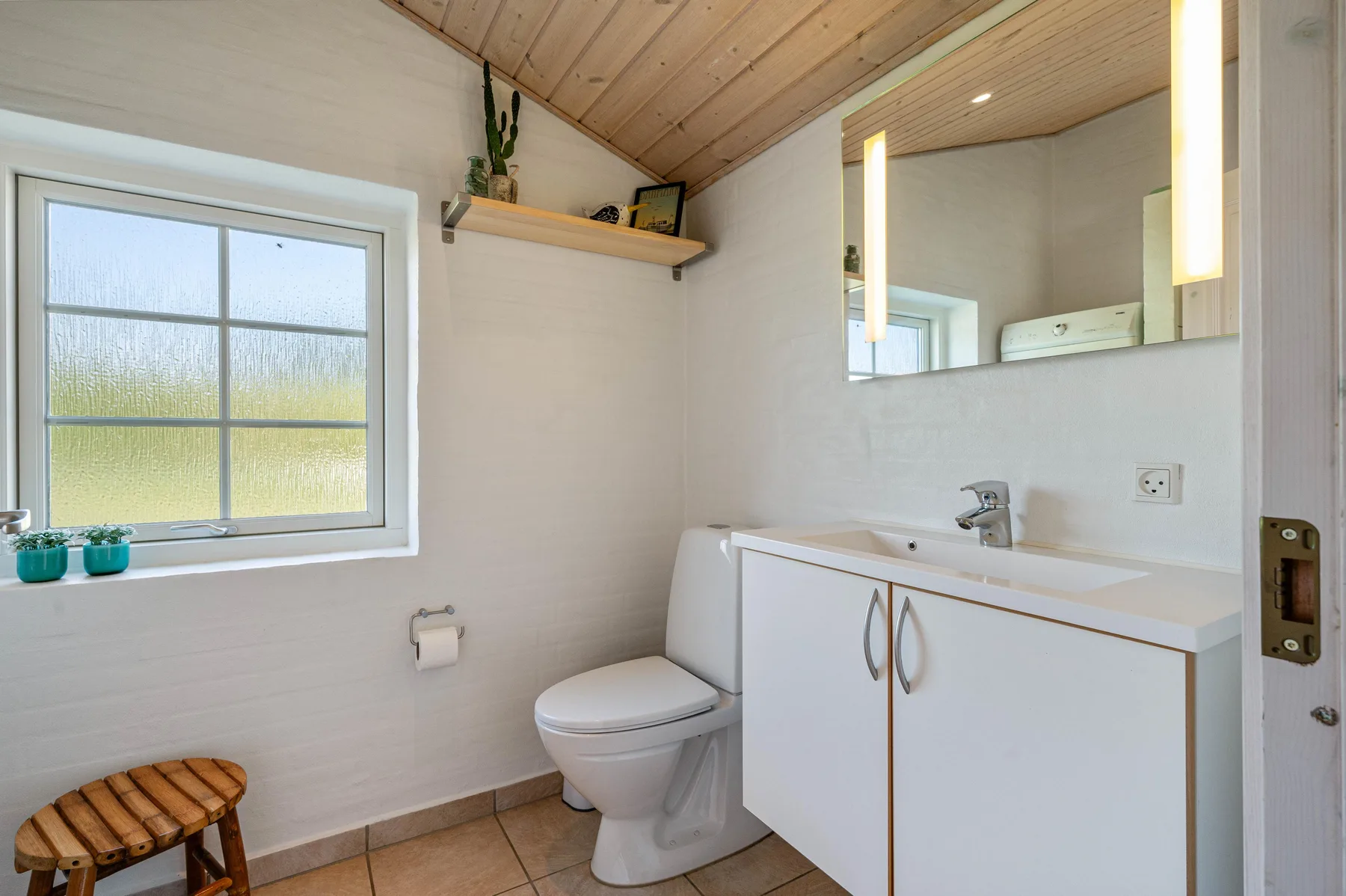 Un baño luminoso con lavabo, inodoro y ventana.