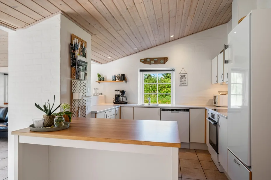 Una cocina luminosa con gabinetes blancos e isla con cubierta de madera.