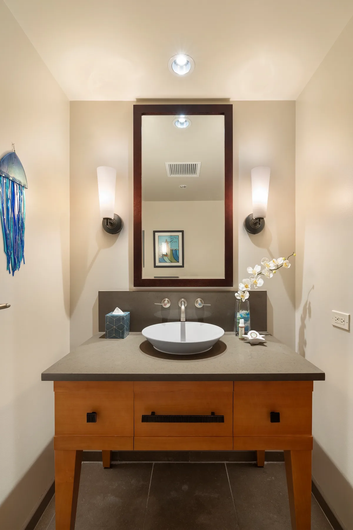 A bathroom vanity with a sink sits beneath a large framed mirror.