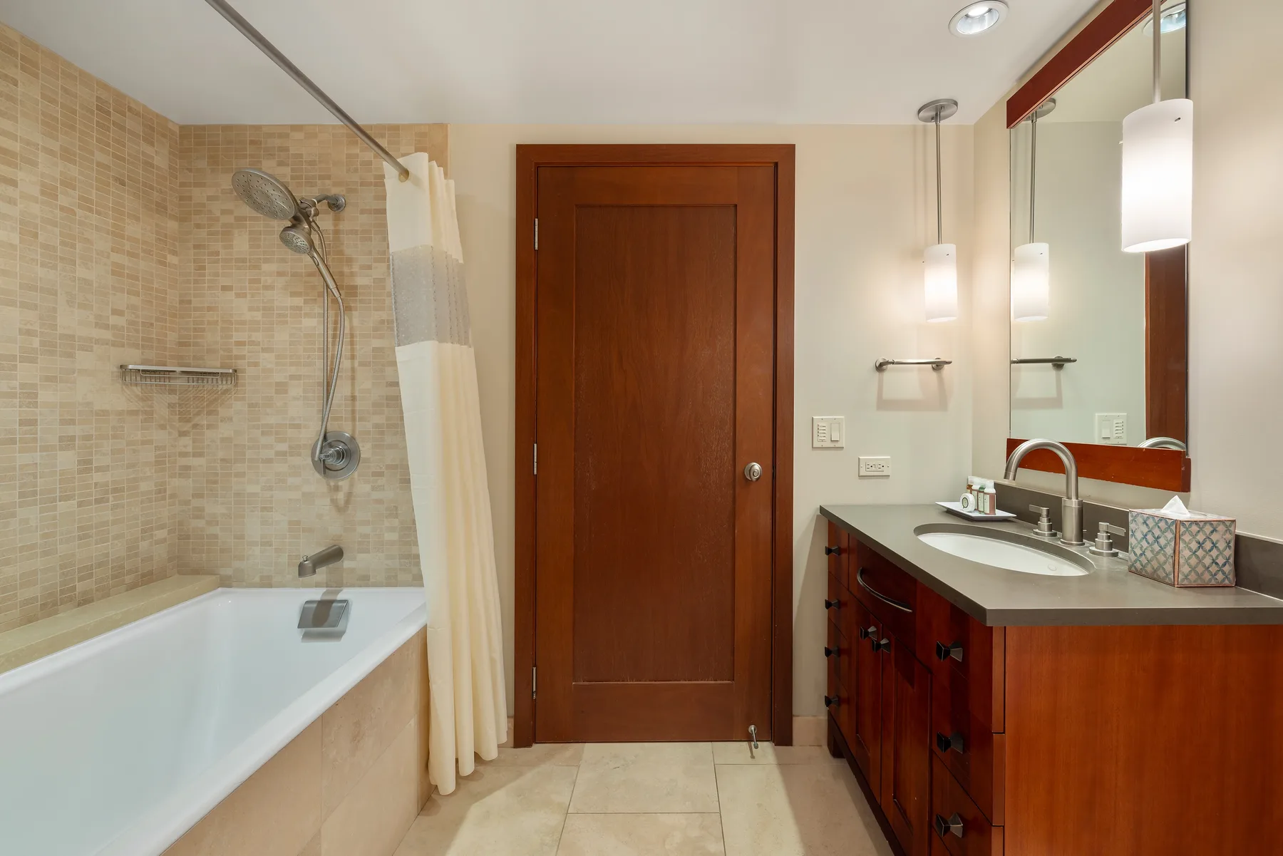 A bathroom with a bathtub, shower, and wooden vanity.
