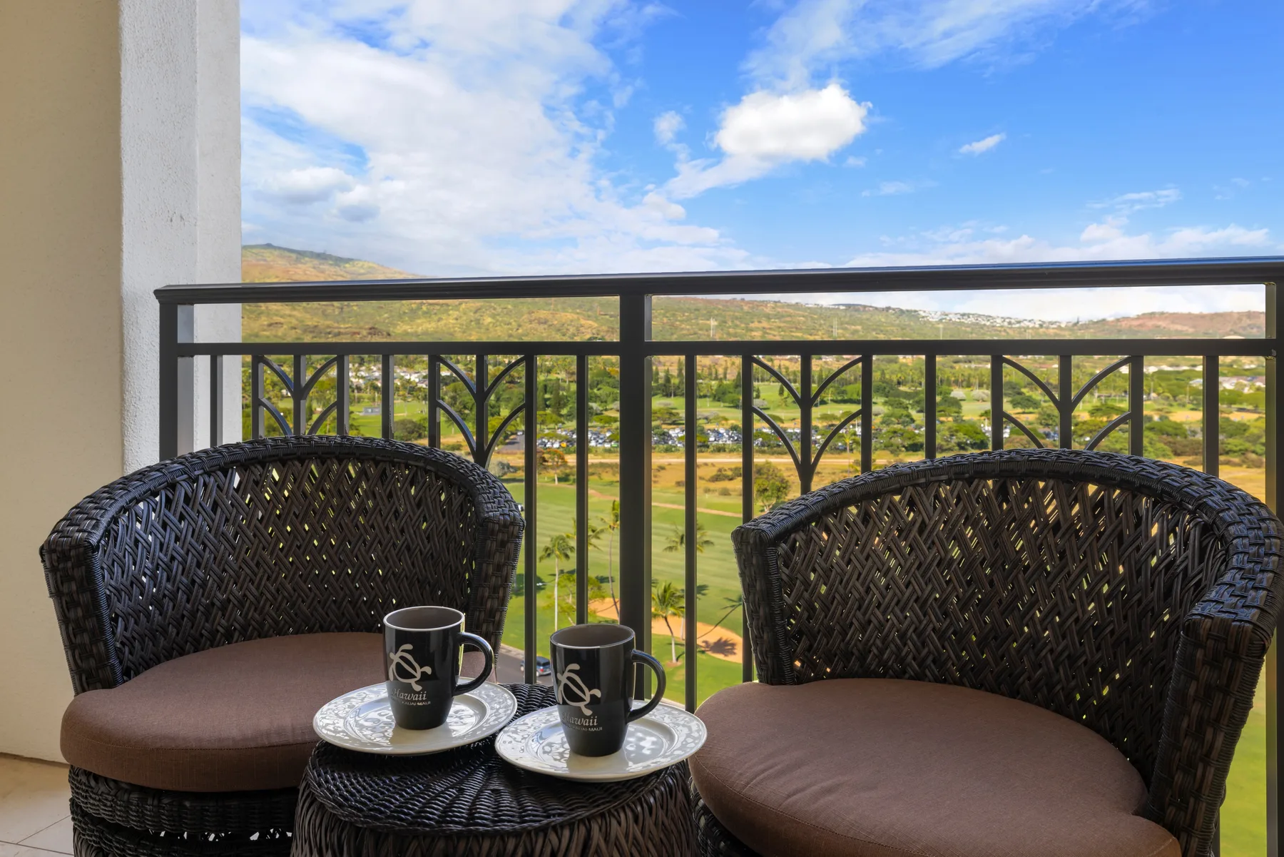 A balcony seating area overlooks a green valley and distant hills.