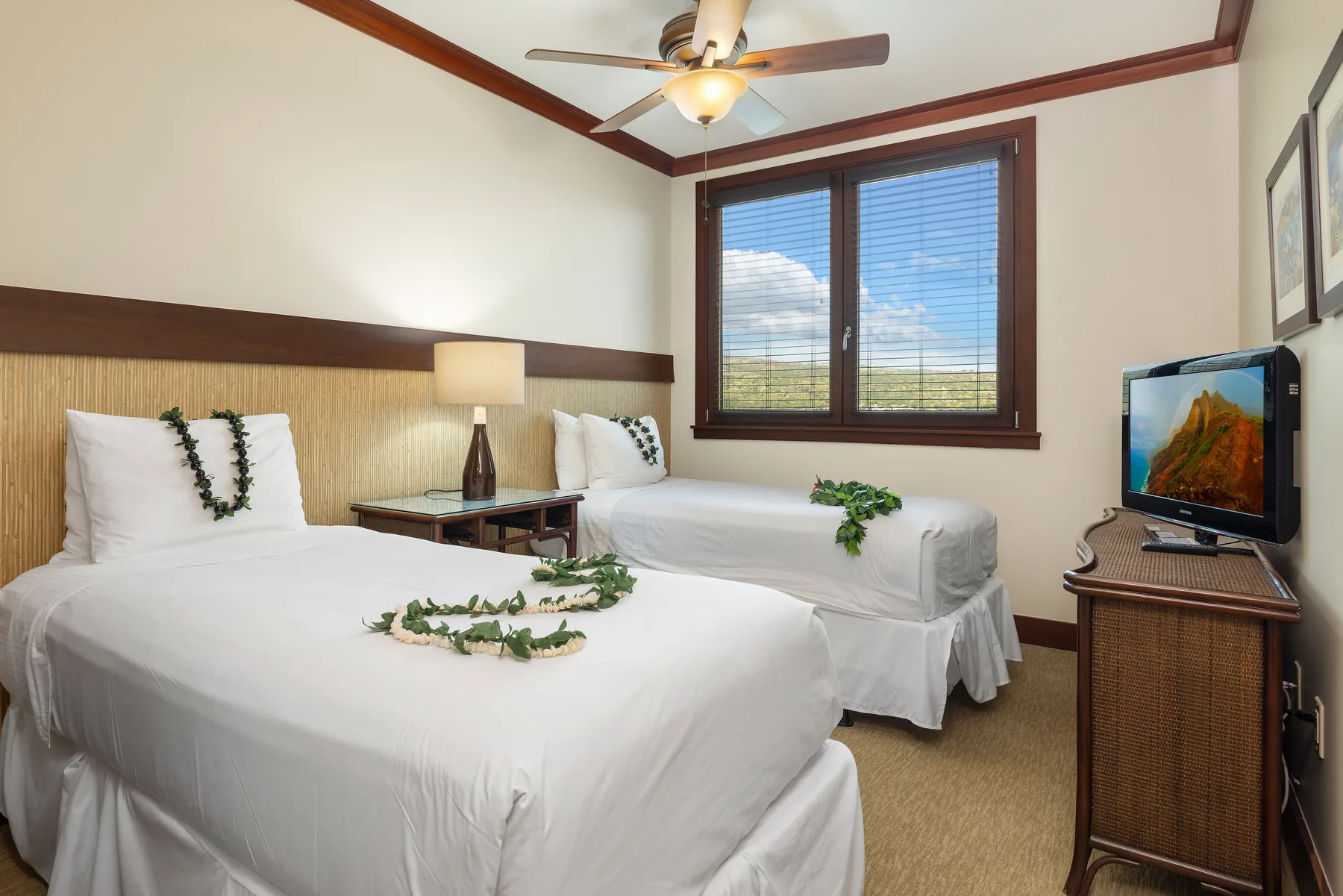 A bedroom with two beds, a window, and a television.