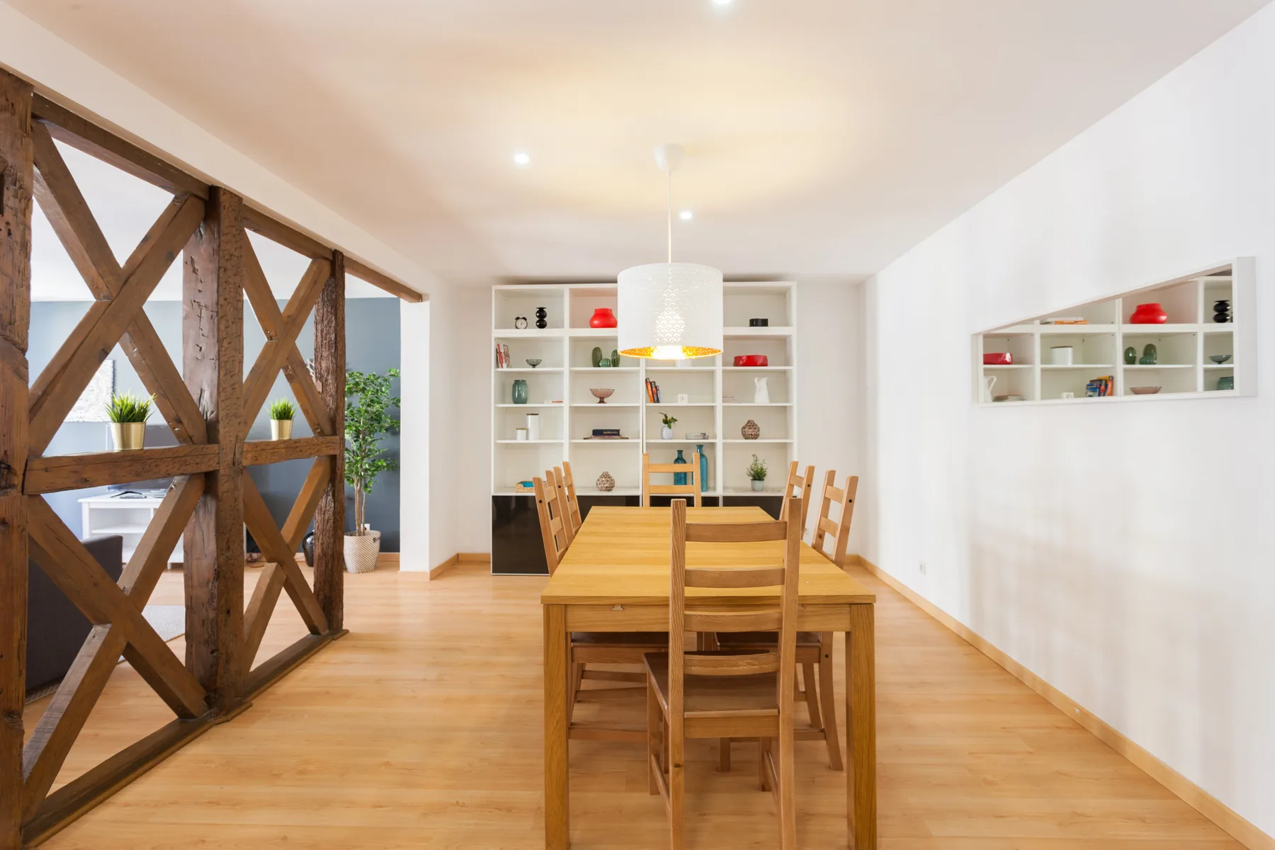 Un comedor luminoso con una mesa de madera y estanterías empotradas.