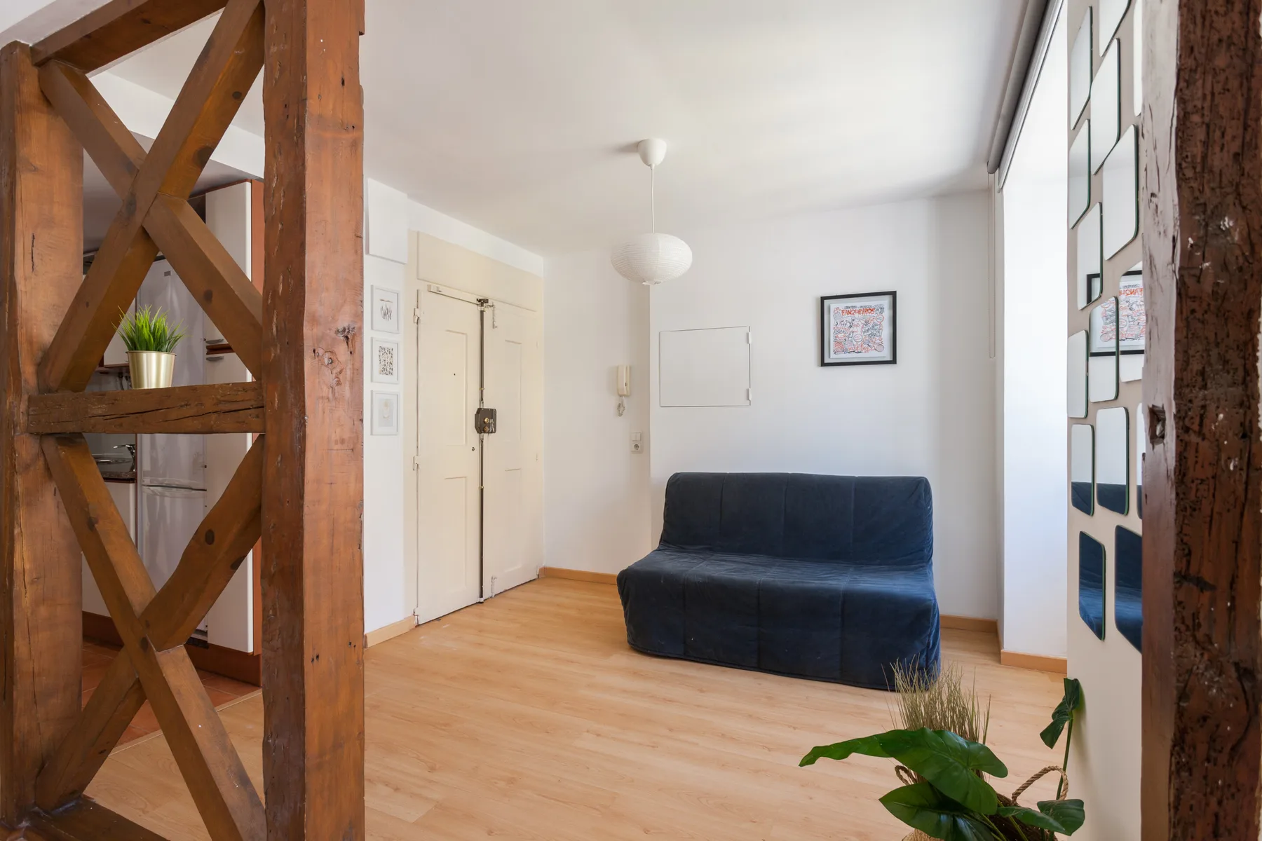 Una sala luminosa con un sofá azul oscuro y suelo de madera.