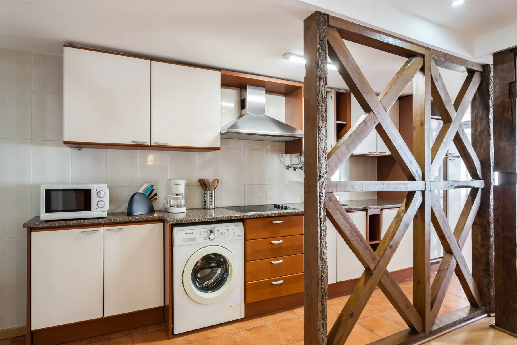 Una cocina compacta con lavadora y separador de madera.