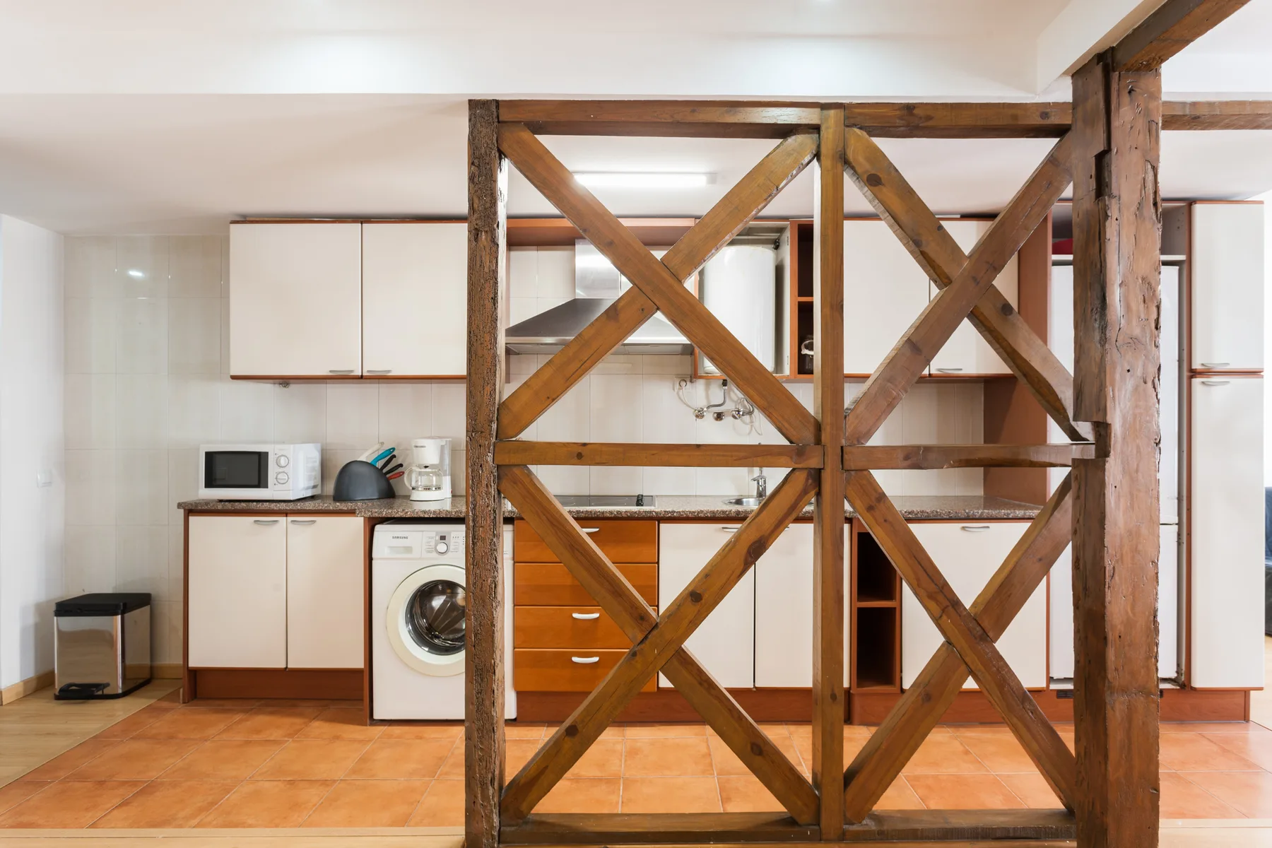 Una cocina compacta con armarios blancos y una división de madera.