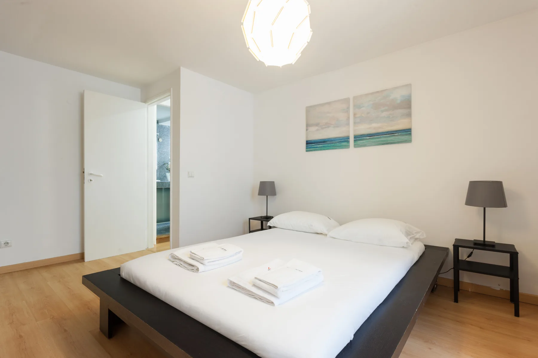 Un dormitorio con una cama tendida y mesitas de noche a juego.