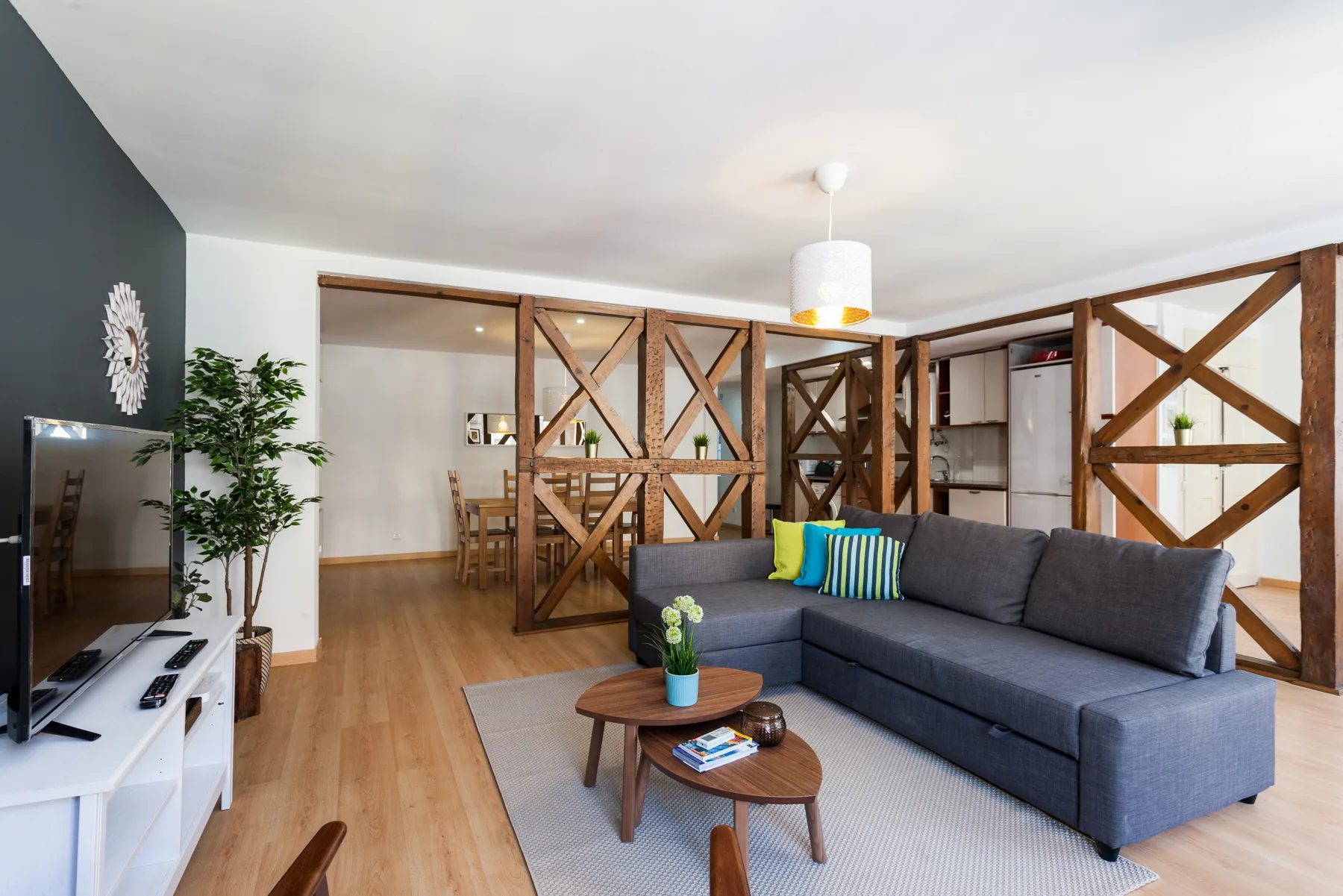 Una sala de estar con un sofá gris y separadores de madera.