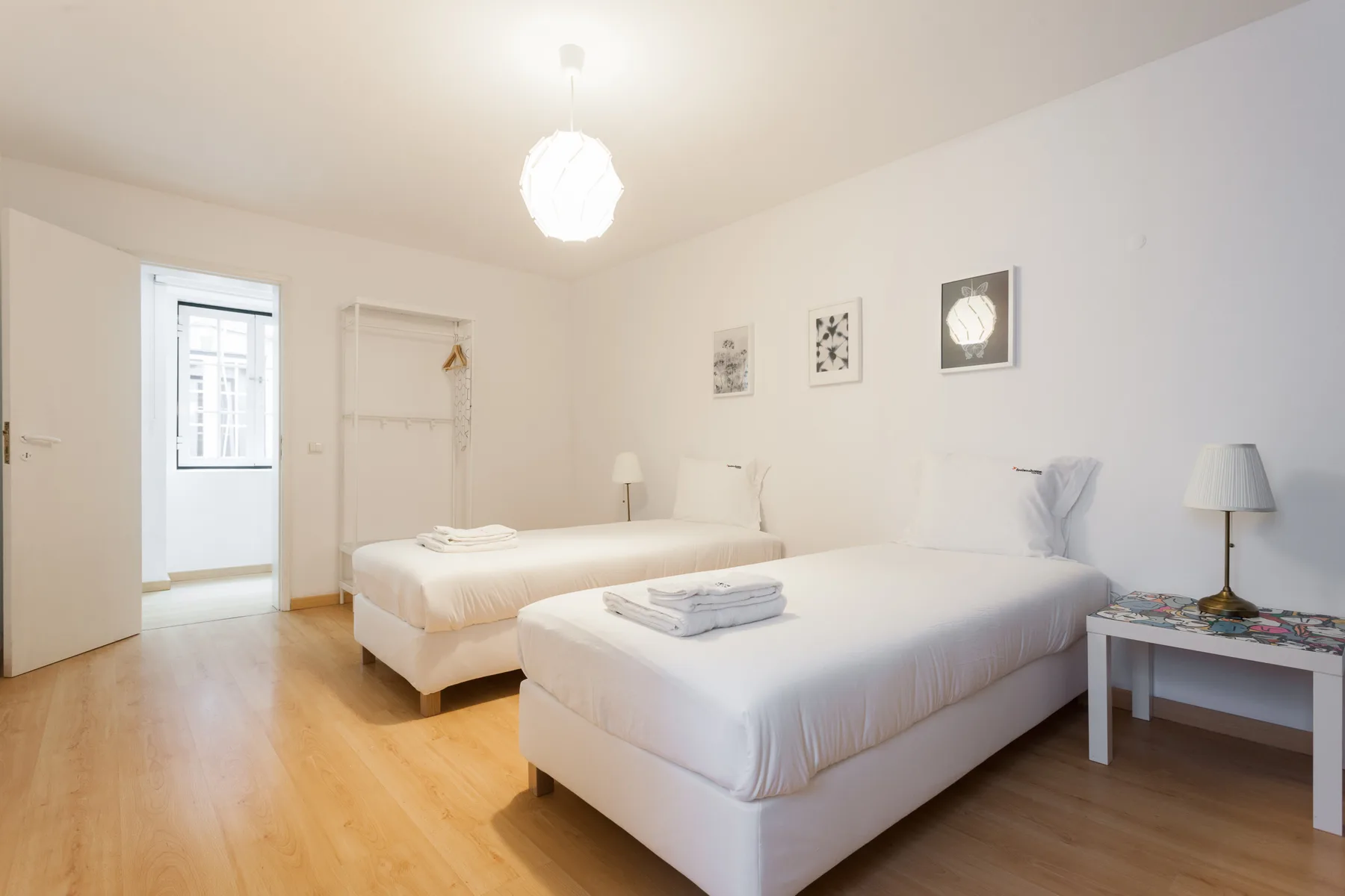 Un dormitorio luminoso con dos camas, toallas dobladas y cuadros enmarcados.