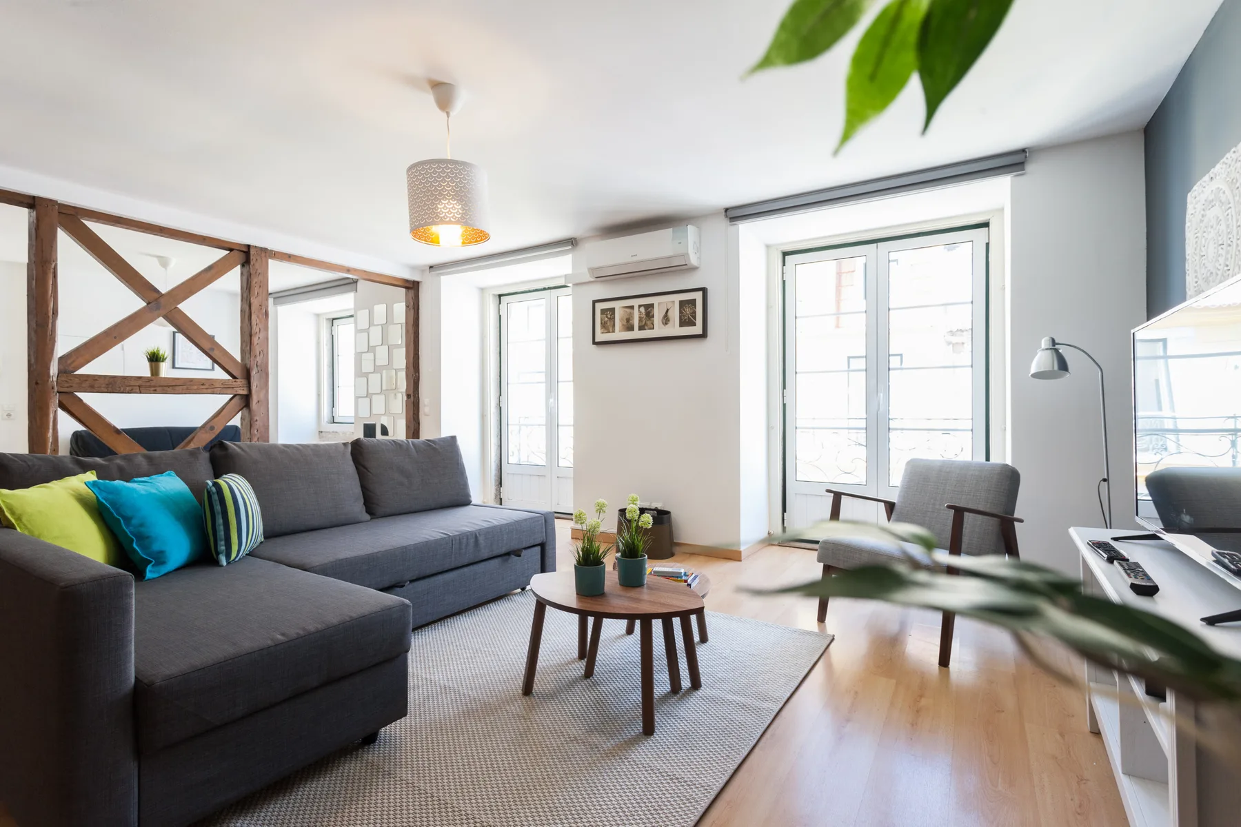 Una sala luminosa con asientos grises, una mesa de centro y grandes ventanas.