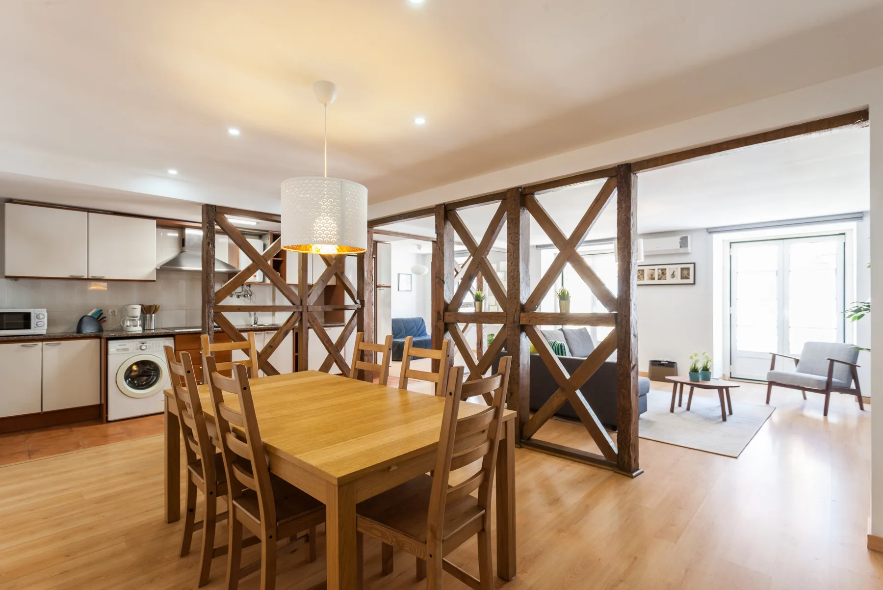 Una zona abierta de comedor y cocina con una mesa de madera y un espacio de estar contiguo.